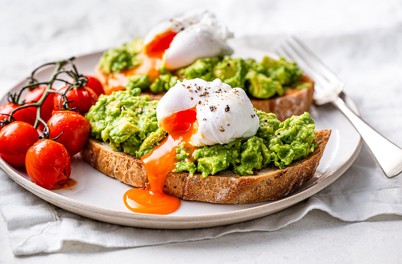 Smashed avocado on toast with poached eggs and tomatoes recipe