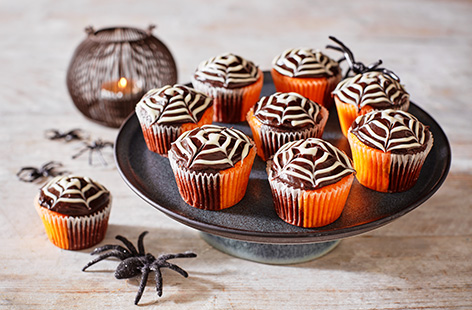 All you need is a white chocolate writing pen and chocolate frosting to make these neat and intricate spiderweb cakes