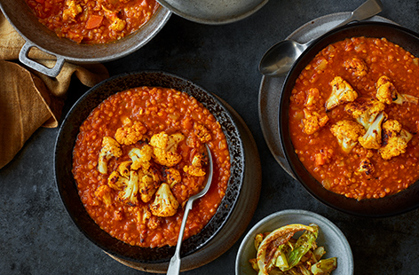 Cook this comforting red lentil and cauliflower dhal recipe for a wallet-friendly veggie dinner, perfect for Meat-Free Monday. Roast a cauliflower - leaves and all - in fragrant korma paste until caramelised, then use it to top a spicy dhal.