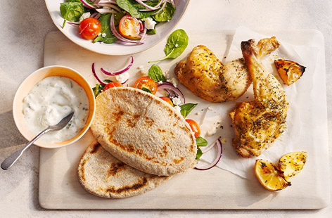 Lemony chicken is roasted until golden and crisp then served with a fresh Greek-inspired salad and pittas. 