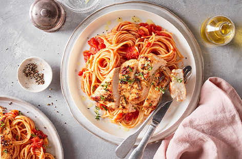 Chicken breasts are marinated in a herby olive oil spiked with lemon juice, then grilled and served with a tomato spaghetti