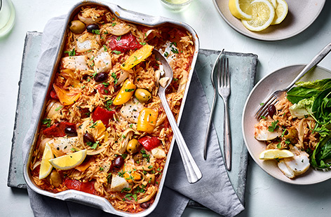 Feed a crowd with this easily transportable orzo paella traybake. It uses orzo pasta instead of rice and budget-friendly frozen fish in a garlicky tomato sauce and is easy to portion up and reheat. 