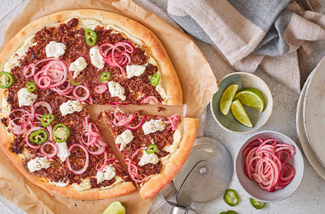 Have a go at this easy pizza recipe. The homemade dough is made from only two ingredients and doesn't require any rising or resting time. It's then topped with a layer of creamy soft cheese, spicy lamb mince, green chillies and quick-pickled onions. Grab a slice!