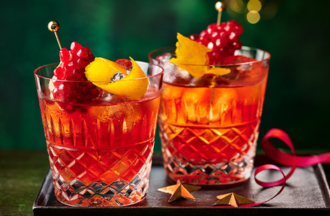 Get the party started with this festive, fruity cocktail inspired by the classic negroni. Bitter-sweet flavours of vermouth, Campari and gin are garnished with pomegranate juice and twists of orange. Cheers!