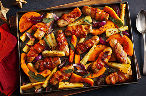 Make pigs in blankets the star of the show with this easy traybake. Cumberland sausages are wrapped in smoked streaky bacon and roasted alongside root veg. Coat in a sticky maple and mustard glaze and serve as a gluten-free main for your Christmas dinner.