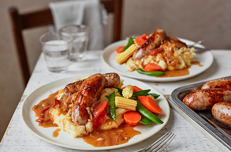 Sausages and mash is a comfort food classic. We've taken it up a notch here by adding a homemade tomato and onion gravy recipe and grating Cheddar into the potatoes for an extra indulgent cheesy mash.
