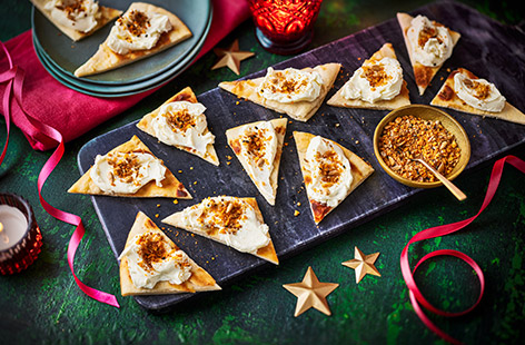 Laffa-style flatbreads are topped with cream cheese and dukkah (a crunchy mix of seeds and spices) in this easy party canapé