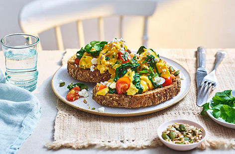 Pep up your scramblers with spinach, tomatoes, coriander and cheese, and serve on wholemeal toast for a hearty breakfast.