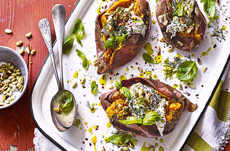 These colourful sweet potatoes are an ideal veggie barbecue recipe. Cool herby yogurt, tahini and pine nuts make a tasty and unusual filling for the smoky potatoes – serve as a vegetarian main or as a hearty side dish to a vibrant barbecue feast.