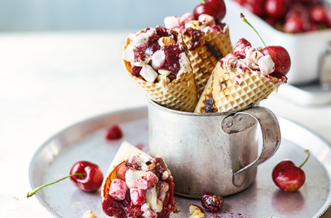 This easy barbecue recipe is inspired by s'mores, an American campfire classic. Barbecued ice cream cones are filled with cherries, crushed cookies and melting, oozy marshmallow and chocolate chips – a quick summer dessert both kids and adults will love. 