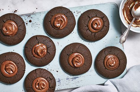 Rich, nutty, with a crisp outside and fudgy milk chocolate ganache topping, these peanut butter and chocolate cookies are a must-bake for chocolate-lovers. The easy thumbprint indents are fun to make and you can even make the cookies ahead.