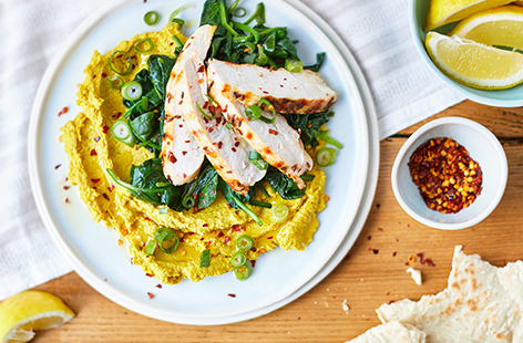 Lunch just got a whole lot more exciting with this gorgeous gluten-free grilled chicken recipe, coated in cumin and garlic, and served on a bed of spinach and creamy curried houmous